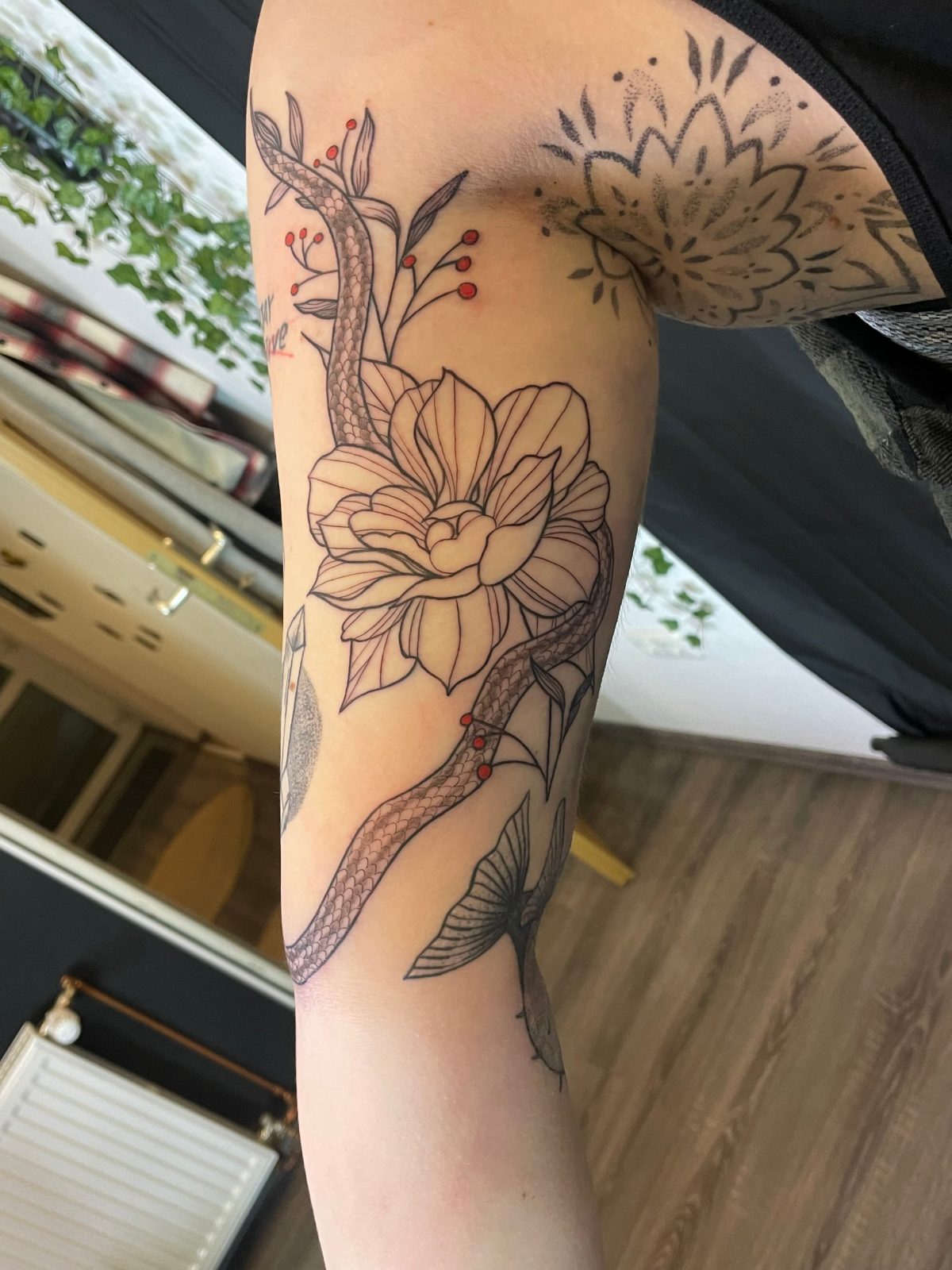 Fine-Line-Tattoo: Schlange und Blüte am Oberarm